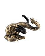 A side-angle view of the antique gold elephant head key hanger against a black background, highlighting the forward curvature of its black tusks and the upward curl of its trunk