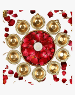 A circular arrangement of glowing golden diyas surrounding a bowl filled with red rose petals and a central candle, creating a warm festive decoration for Diwali. 🪔🌹✨