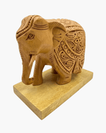 Traditional wooden elephant statue with carved tusks and trunk on wooden plinth base