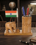 Decorative wooden elephant pen holder with Indian flag on office table next to notebook and lamp