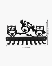 Black metal owl wall hook rack with three owls perched on a branch, shown with dimension labels indicating 10 inches wide and 5.5 inches tall on a light gray background.