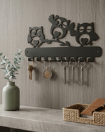 Decorative 3 owl metal key hanger mounted on wall near entryway console table