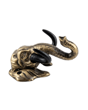 A side-angle view of the antique gold elephant head key hanger against a black background, highlighting the forward curvature of its black tusks and the upward curl of its trunk