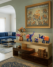 Three decorative blue Meenakari elephants styled on a modern gold and wood console table in a luxury living room