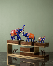 Close-up of a large royal blue metal elephant statue featuring hand-painted red floral patterns and gold accents