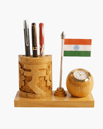 Close-up of carved Rupee symbol wooden pen holder with analog clock and miniature Indian Tricolor flag