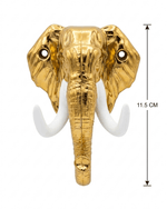 A straight-on view of a gold elephant head wall hook against a white background, featuring white tusks and two mounting screw holes in the ears. A vertical double-sided arrow on the right indicates a height measurement of 11.5 CM