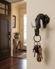 Black elephant wall key holder with tusk hooks holding keys, mounted near home entrance door