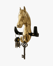 Gold horse head wall key holder mounted at home entrance with keys hanging near wooden door