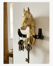 Gold horse wall key holder with hooks holding keys isolated on white background