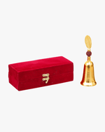 Gold plated temple bell with rudraksha handle beside red velvet storage box