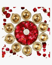 A circular arrangement of glowing golden diyas surrounding a bowl filled with red rose petals and a central candle, creating a warm festive decoration for Diwali. 🪔🌹✨