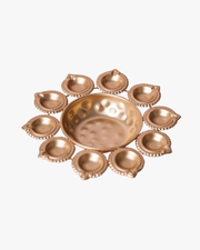 A circular arrangement of glowing golden diyas surrounding a bowl filled with red rose petals and a central candle, creating a warm festive decoration for Diwali. 🪔🌹✨