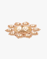 A circular arrangement of glowing golden diyas surrounding a bowl filled with red rose petals and a central candle, creating a warm festive decoration for Diwali. 🪔🌹✨