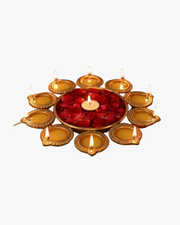 A circular arrangement of glowing golden diyas surrounding a bowl filled with red rose petals and a central candle, creating a warm festive decoration for Diwali. 🪔🌹✨