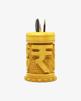 Hand carved wooden pencil holder with Indian rupee symbol design used as a desk organizer for pens and pencils.