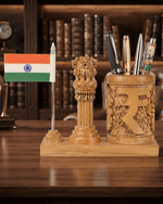 A carved wooden desk organizer set on a wooden table, featuring a small Indian flag on a silver stick, a carved lion capital pillar, and a carved cylindrical cup holding pens and pencils.