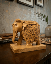 Handcrafted wooden elephant figurine displayed on wooden desk with books and decor
