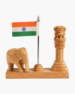 Front view of handcrafted wooden desk stand with Indian flag on metal pole, Ashok Stambh pillar, and elephant sculpture on a white background.