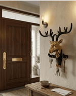Decorative gold and black deer head key hanger mounted on a textured entryway wall next to a wooden door and bench