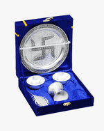 Angled view of open blue velvet gift box with engraved silver pooja thali set and accessories