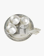 Top view of silver pooja thali set with diya bowls kalash and decorative spoon on engraved plate