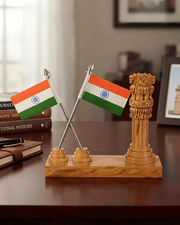 Wooden Ashok Stambha and Indian national flag table stand placed on a wooden office study desk next to books and notebook.