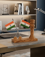 Handcrafted wooden Ashoka emblem pillar with twin tricolor flags on a modern executive office desk setup.