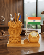 A carved wooden desk organizer set on a polished wooden table, featuring a lion-shaped pen holder filled with writing instruments, a small Indian flag on a silver pole, and a round wooden clock with a gold-toned face. The set is displayed in an office environment with books and a lamp in the background.
