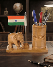 Decorative wooden elephant pen holder with Indian flag on office table next to notebook and lamp