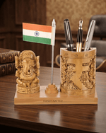 Handcrafted wooden desk organizer featuring Lord Ganesha idol, pen stand with pens, and mini Indian flag on an office desk.