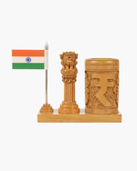 A wooden desk set featuring a small Indian flag on a silver pole, a carved wooden pillar with a lion capital, and a matching carved cylindrical cup, all mounted on a rectangular wooden base against a plain white background.