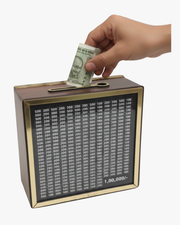 Hand depositing cash into wooden savings challenge box with ₹1 lakh goal